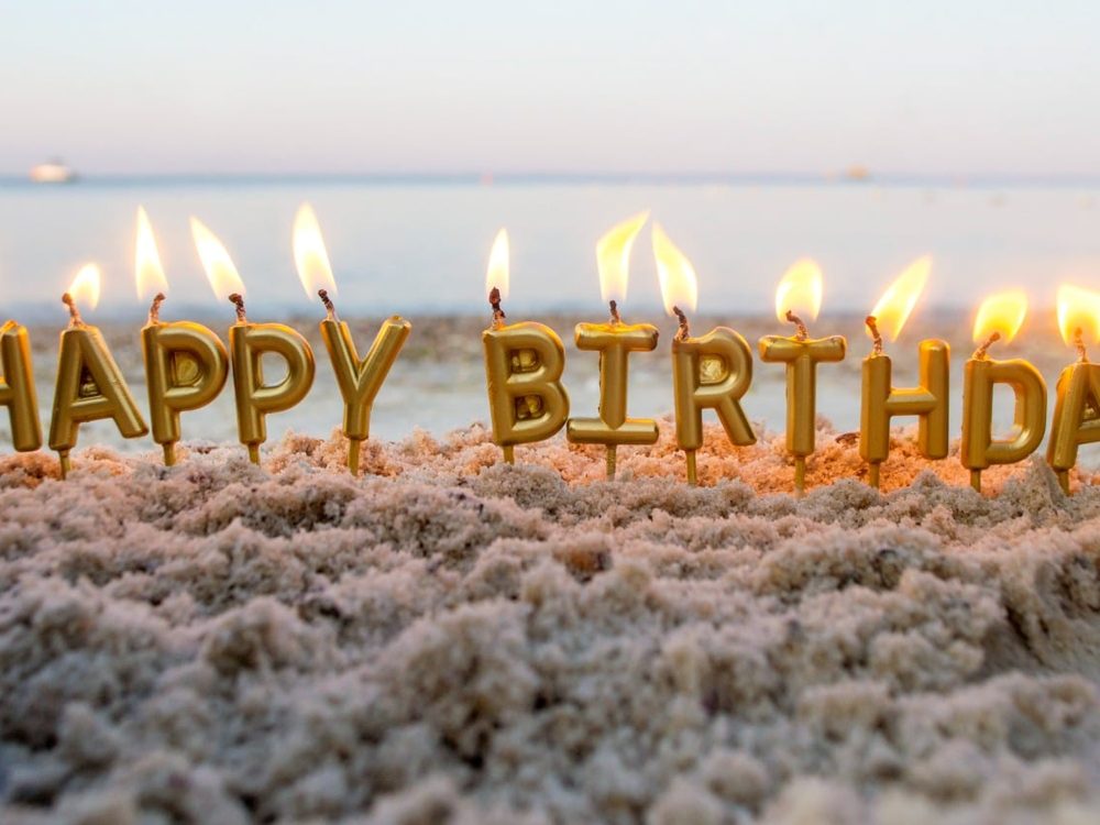 Happy Birthday candles lit on the beach