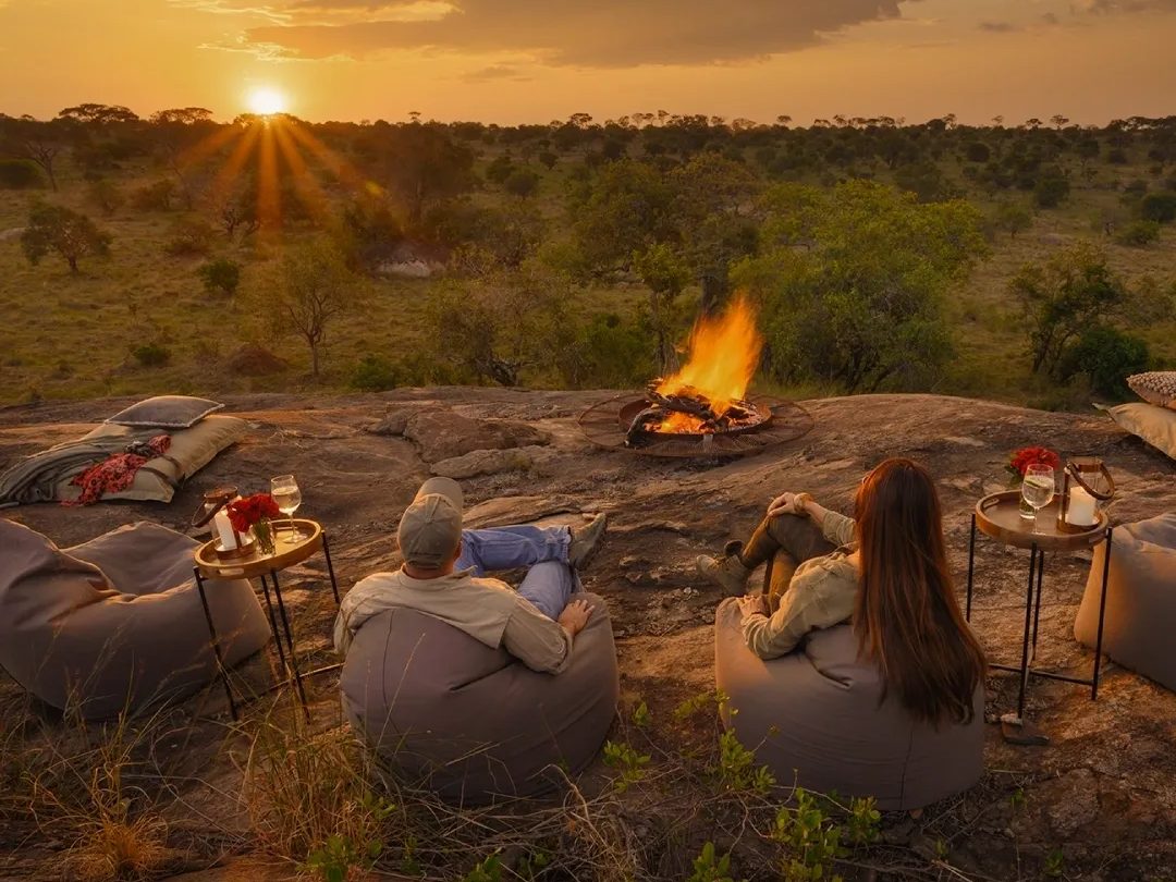 Couple relaxing by a sunset campfire on a romantic safari getaway